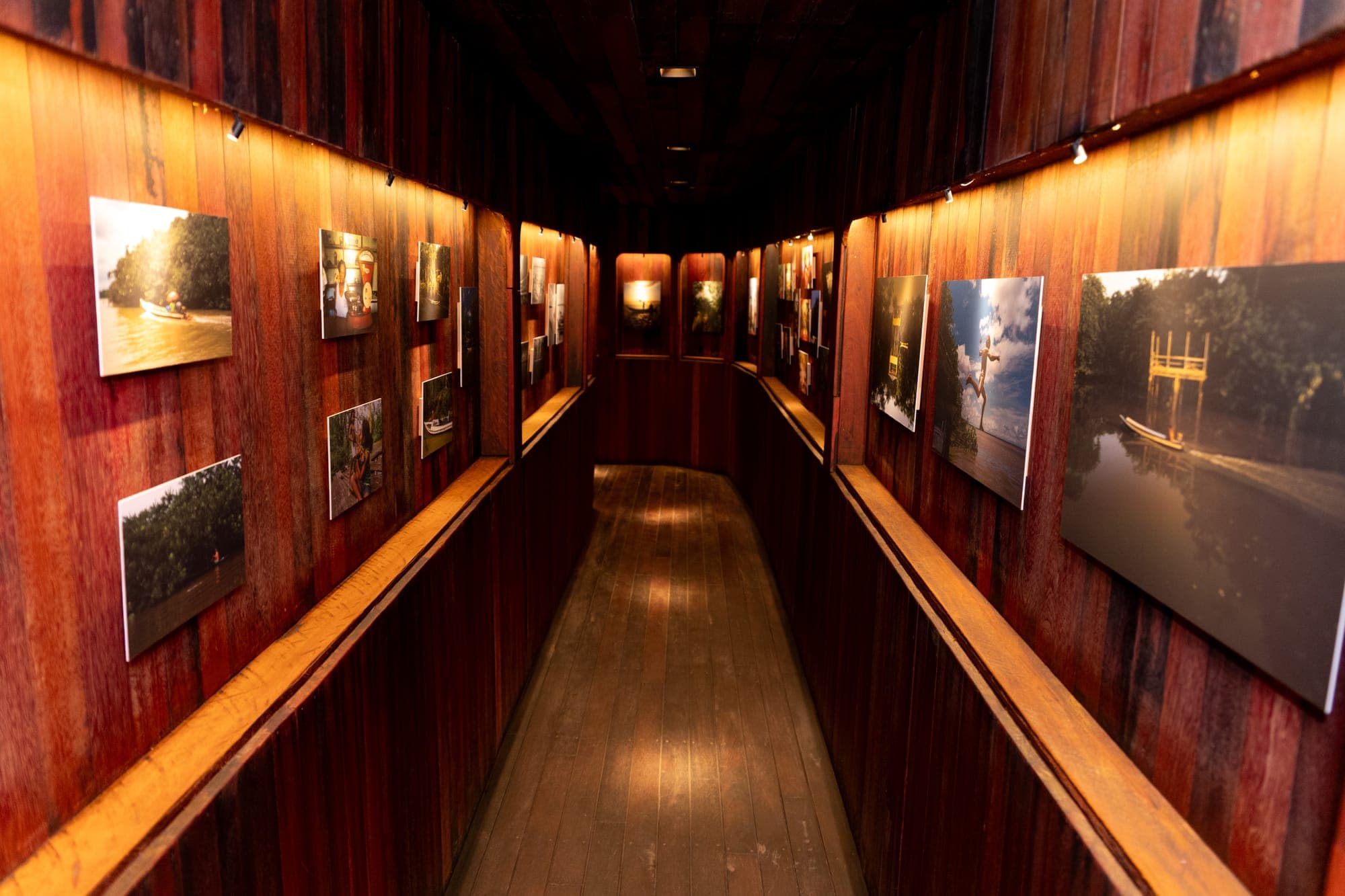 Corredor da galeria com fotografias iluminadas nas paredes de madeira