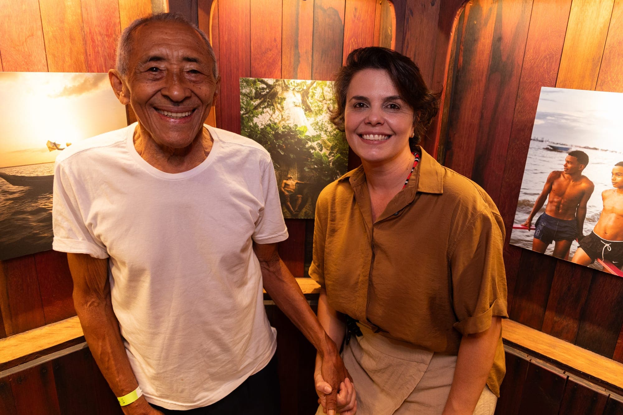Visitantes sorriem diante das fotografias na inauguração