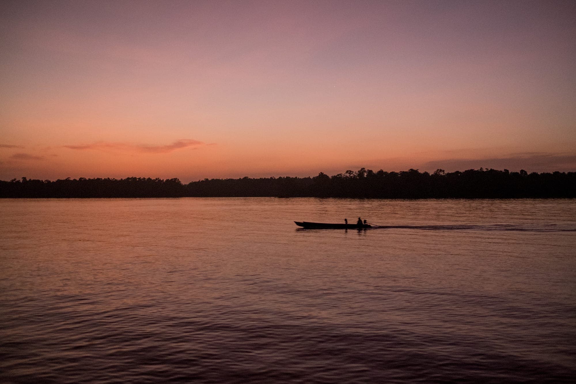 Canoa atravessa o rio ao entardecer