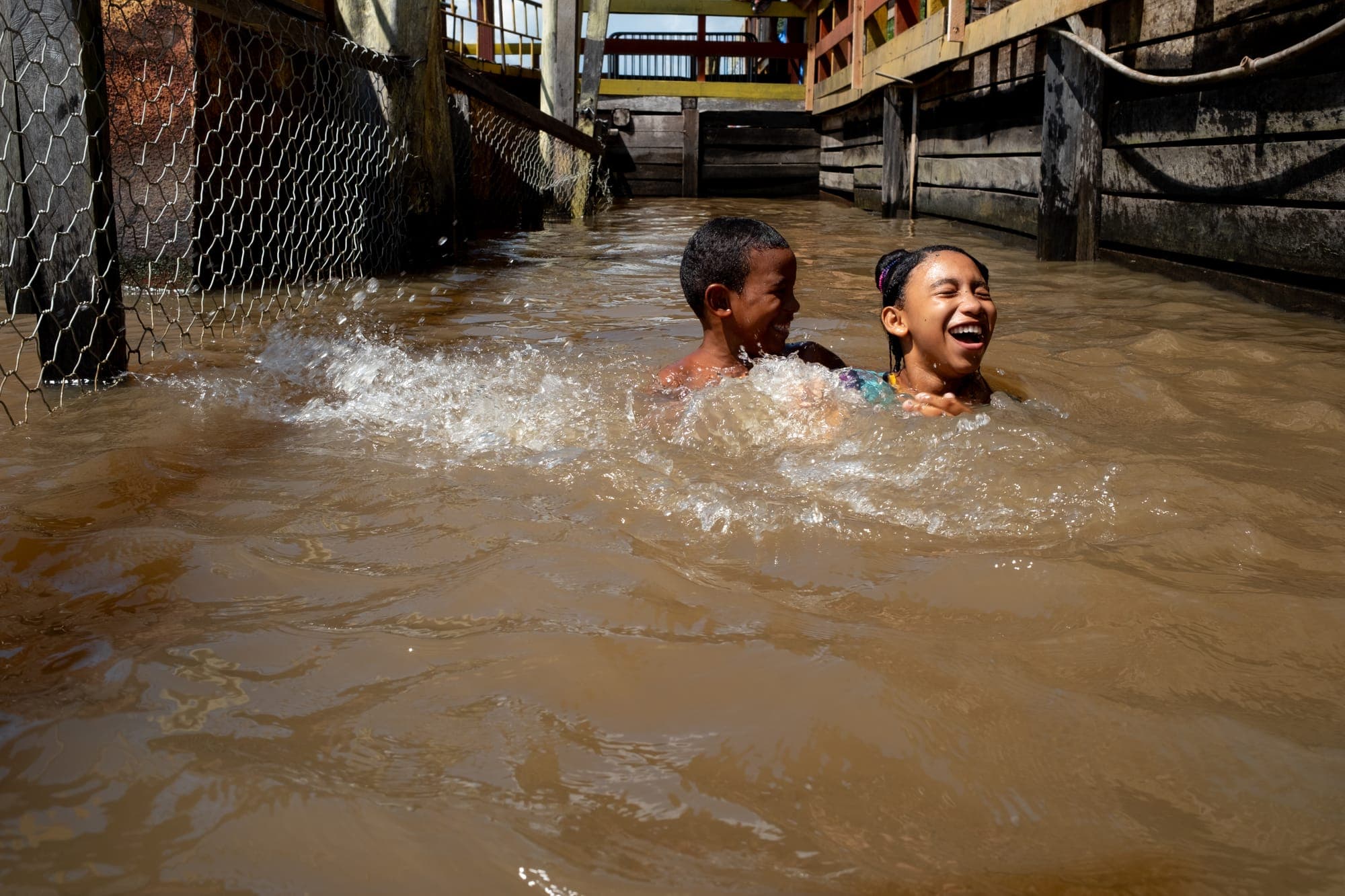Crianças riem brincando na água do rio