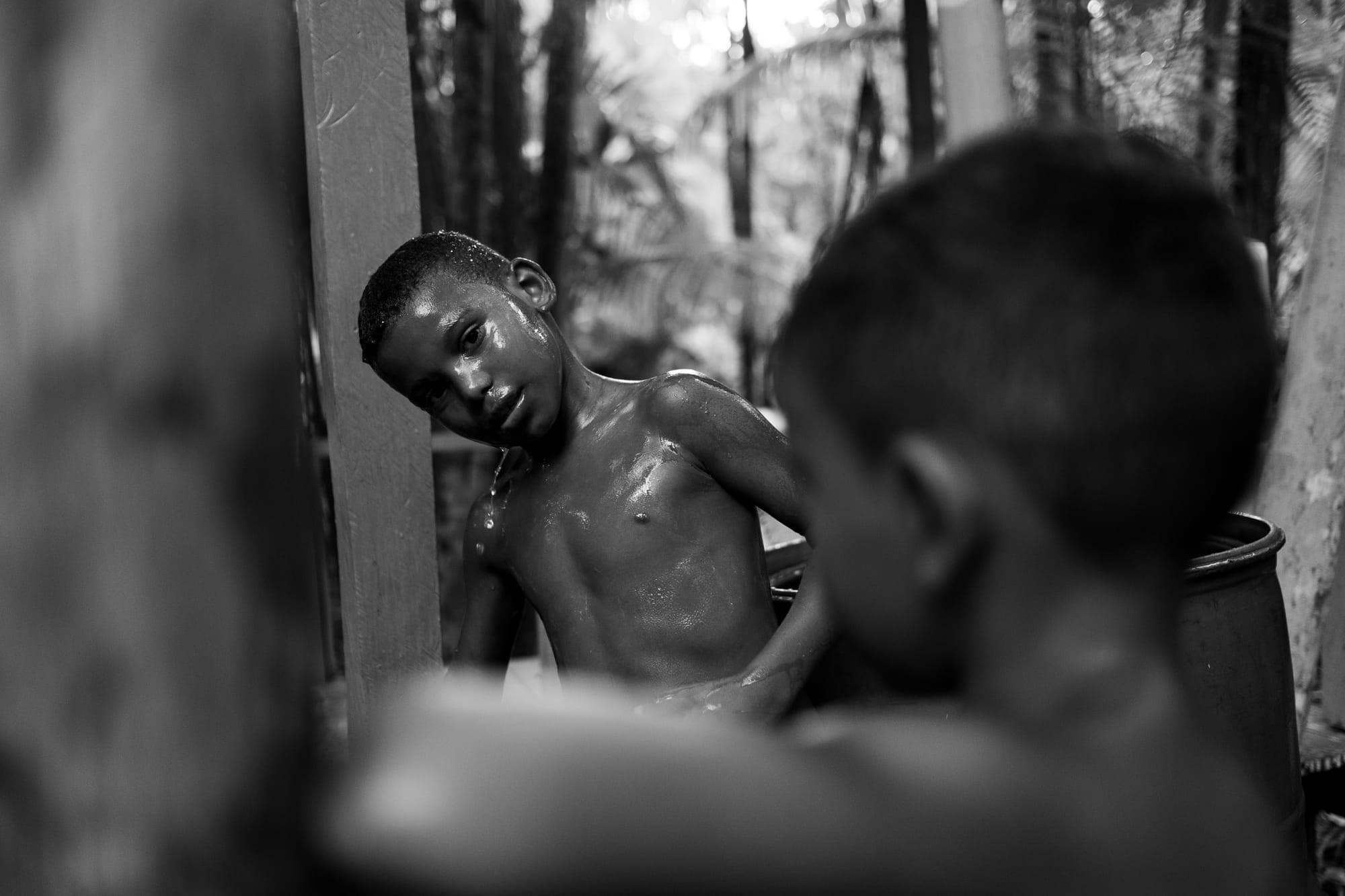 Meninos se refrescam com água, em preto e branco