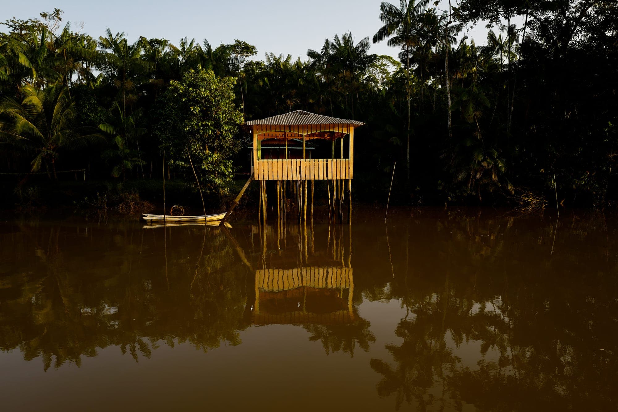 Casa de palafita refletida na água do rio