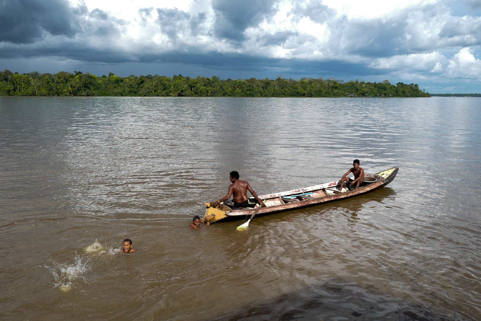 Canoa e crianças nadando no rio largo