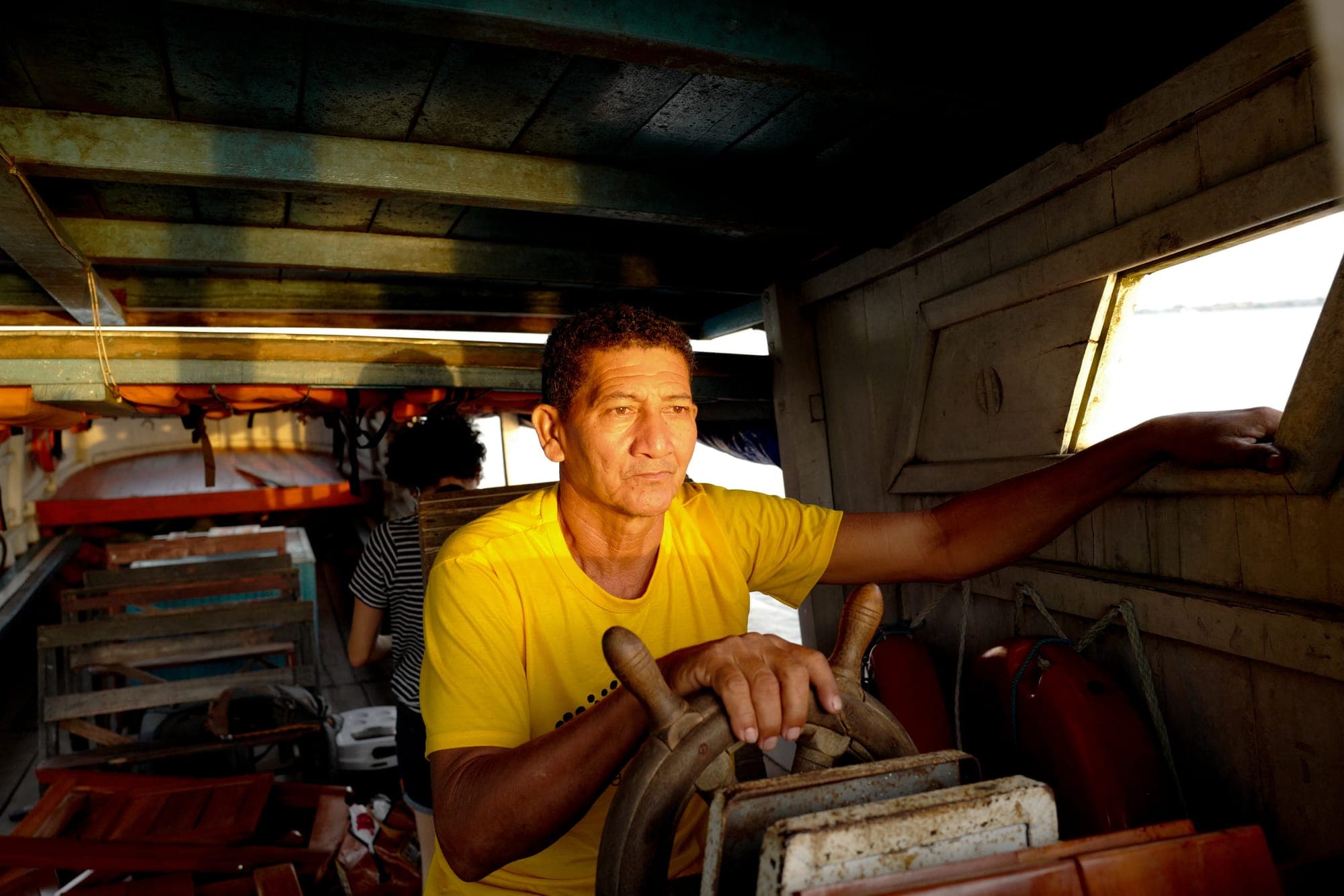 Homem sorri pilotando o barco