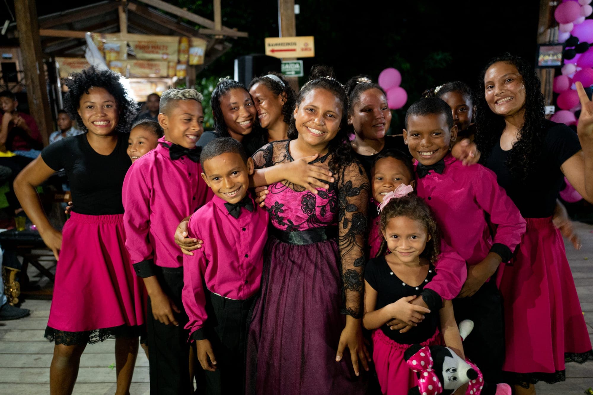 Grupo de crianças e jovens com roupas de festa rosa e preto
