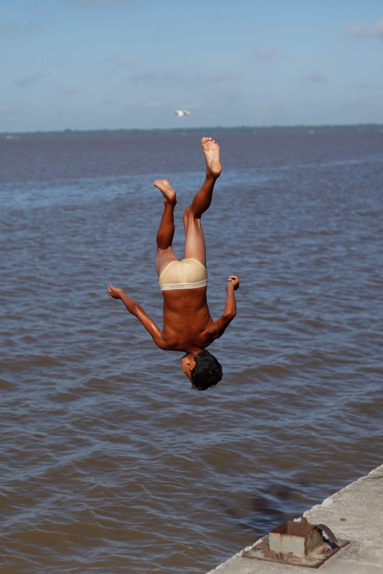 Menino dá um salto mortal para o rio