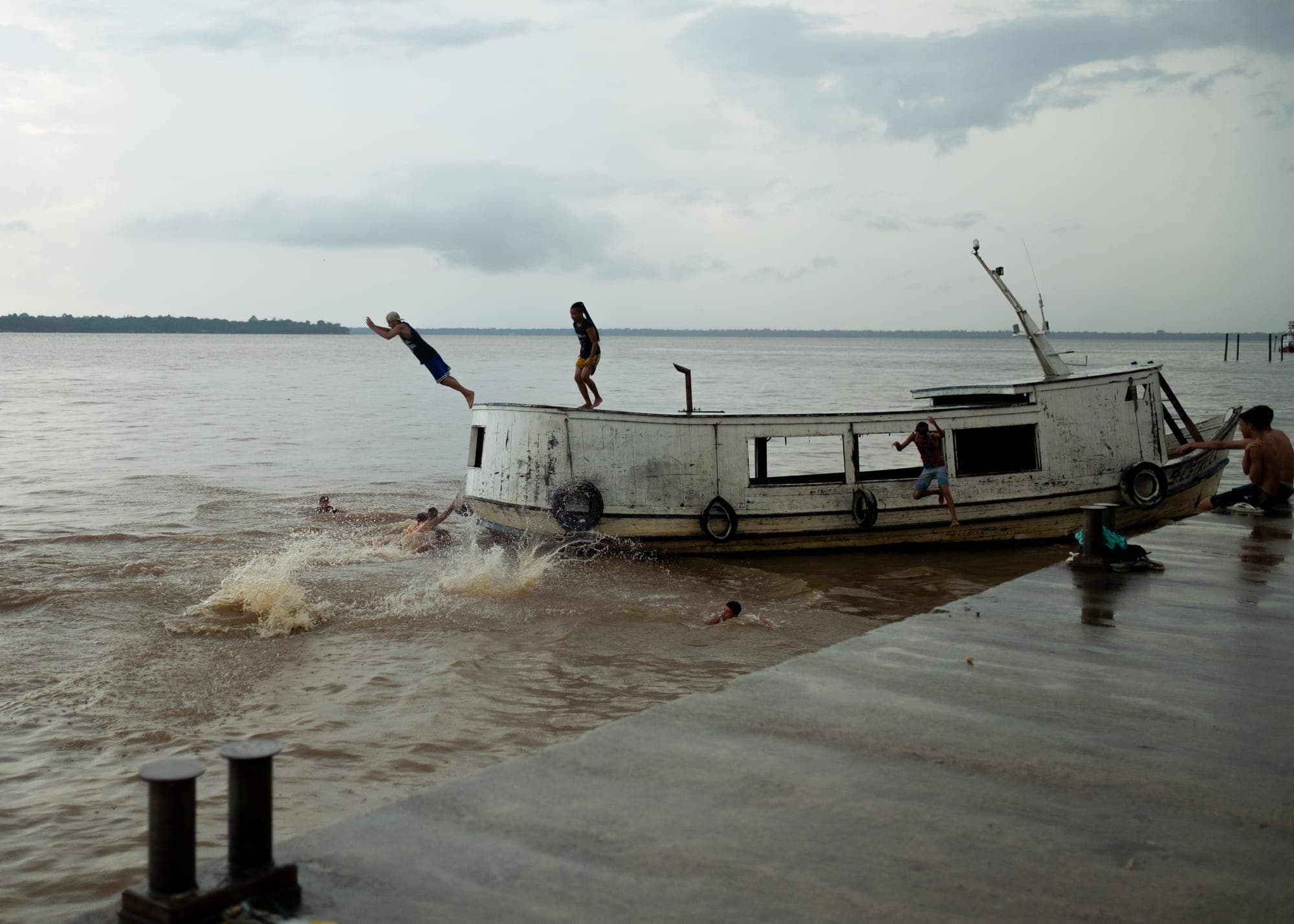 Crianças saltam de um barco para o rio