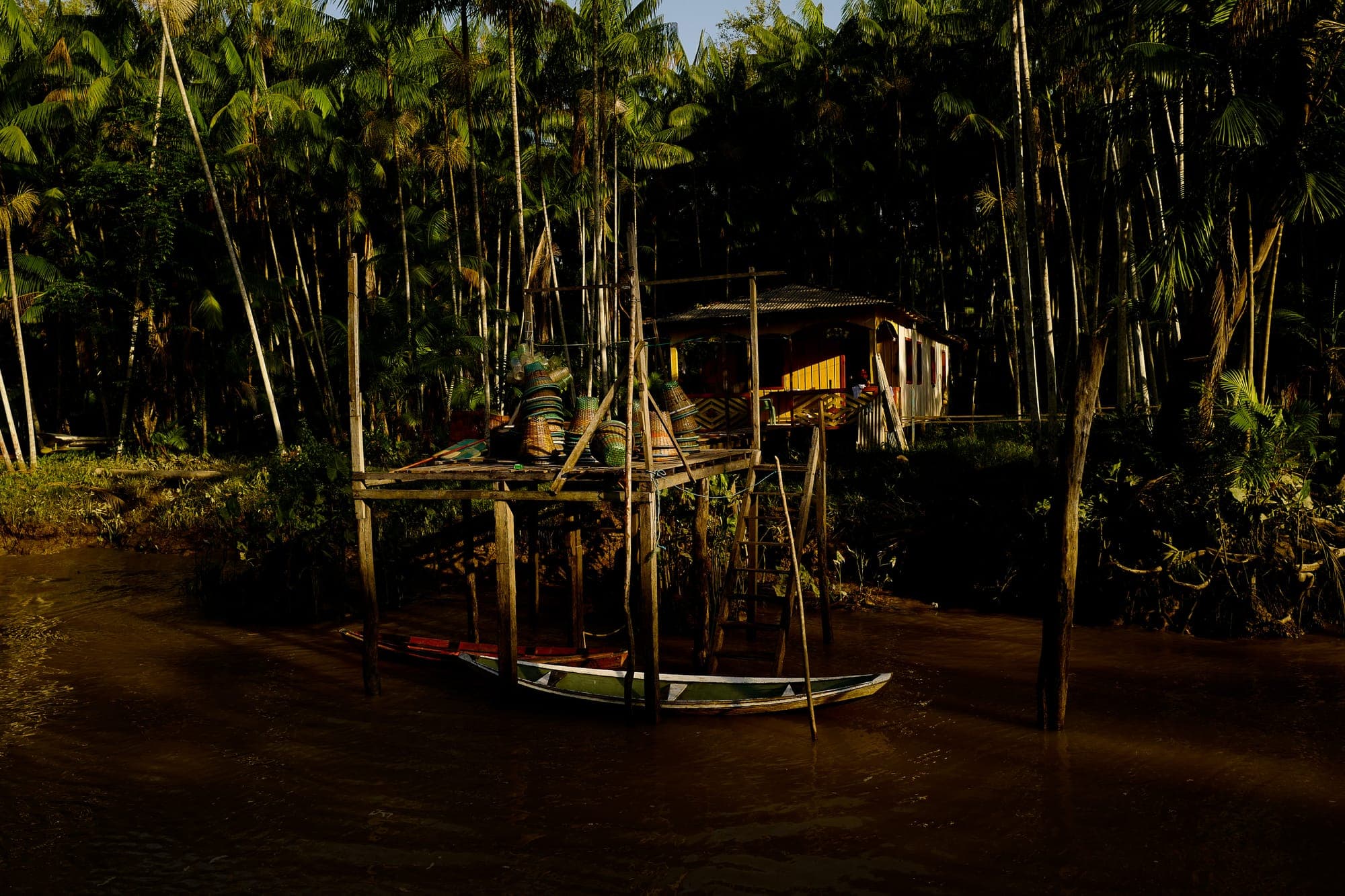 Canoa atracada junto a uma casa entre a mata