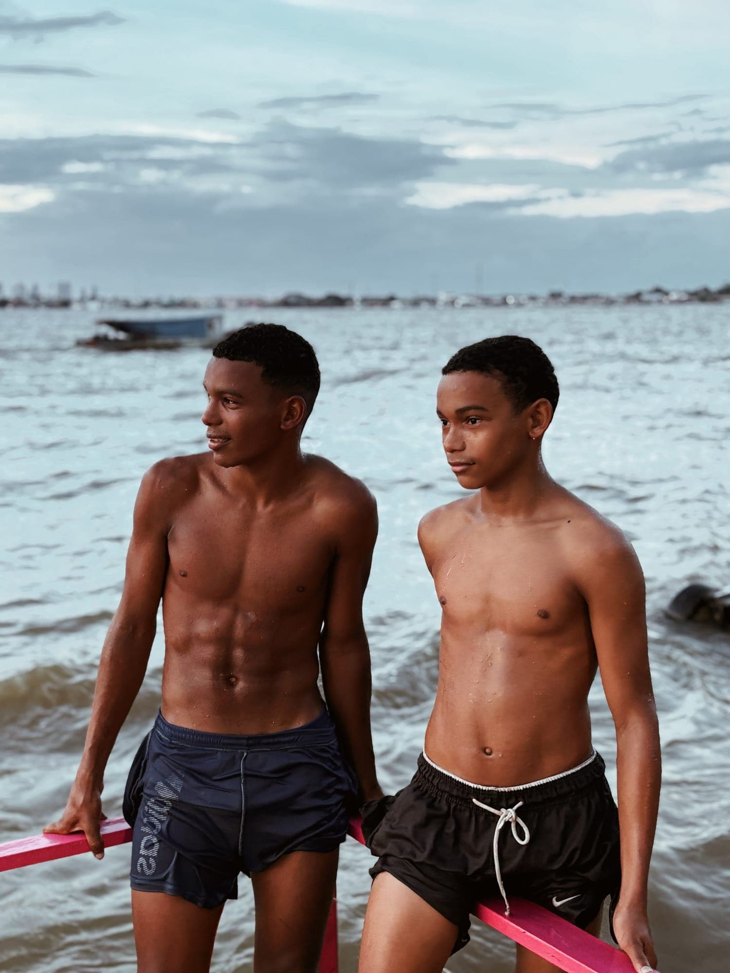 Dois rapazes sorriem na beira do rio