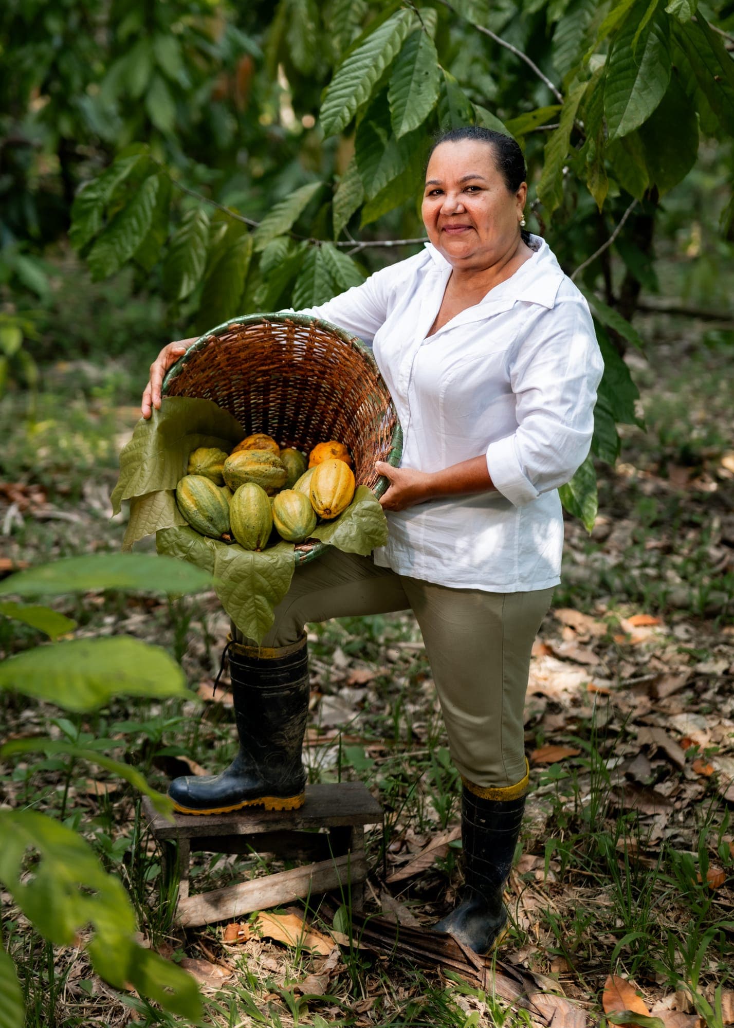 Mulher sorri segurando um paneiro cheio de cacau