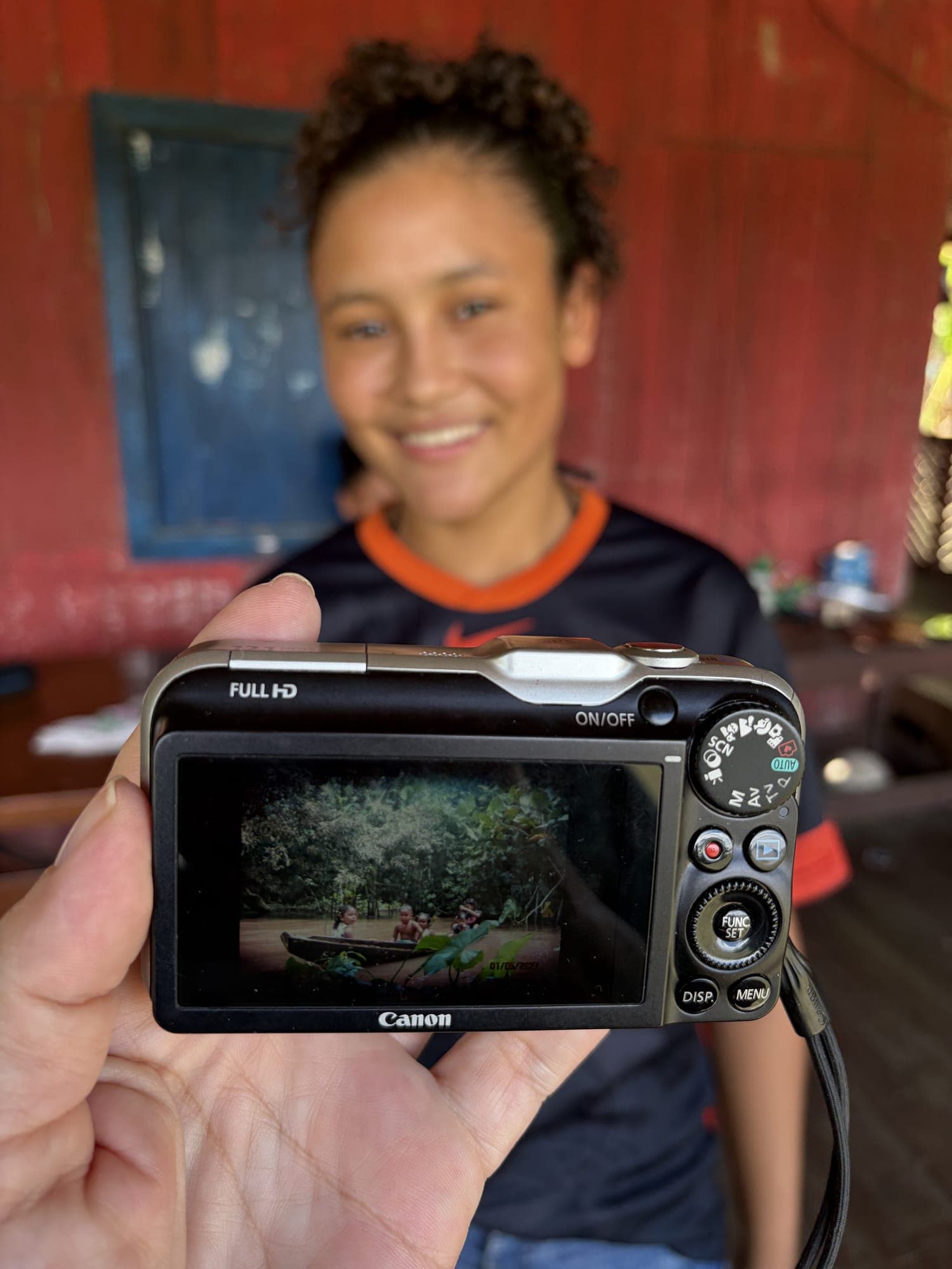 Menina sorri atrás de uma câmera que mostra sua fotografia