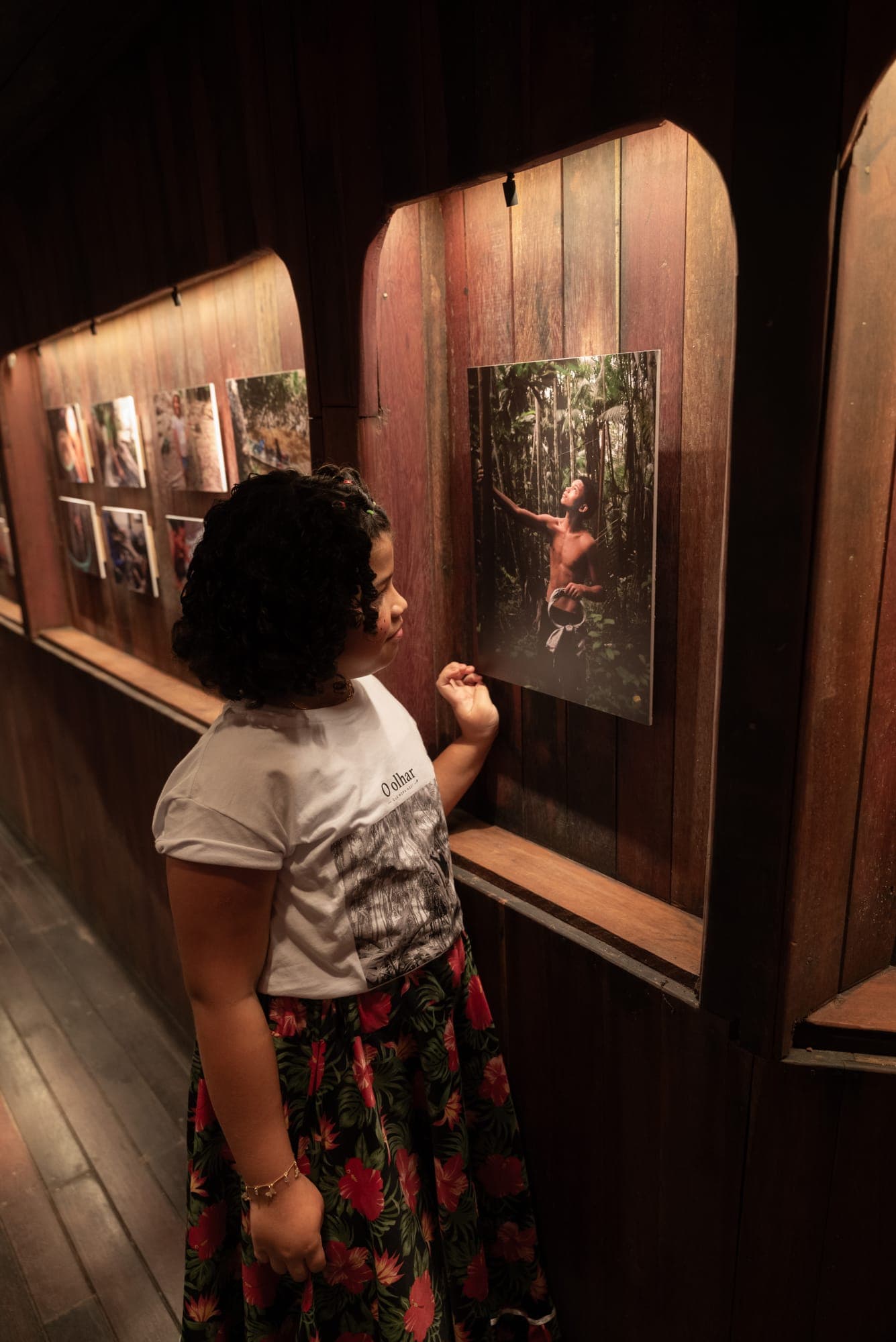 Menina observa as fotografias expostas na galeria