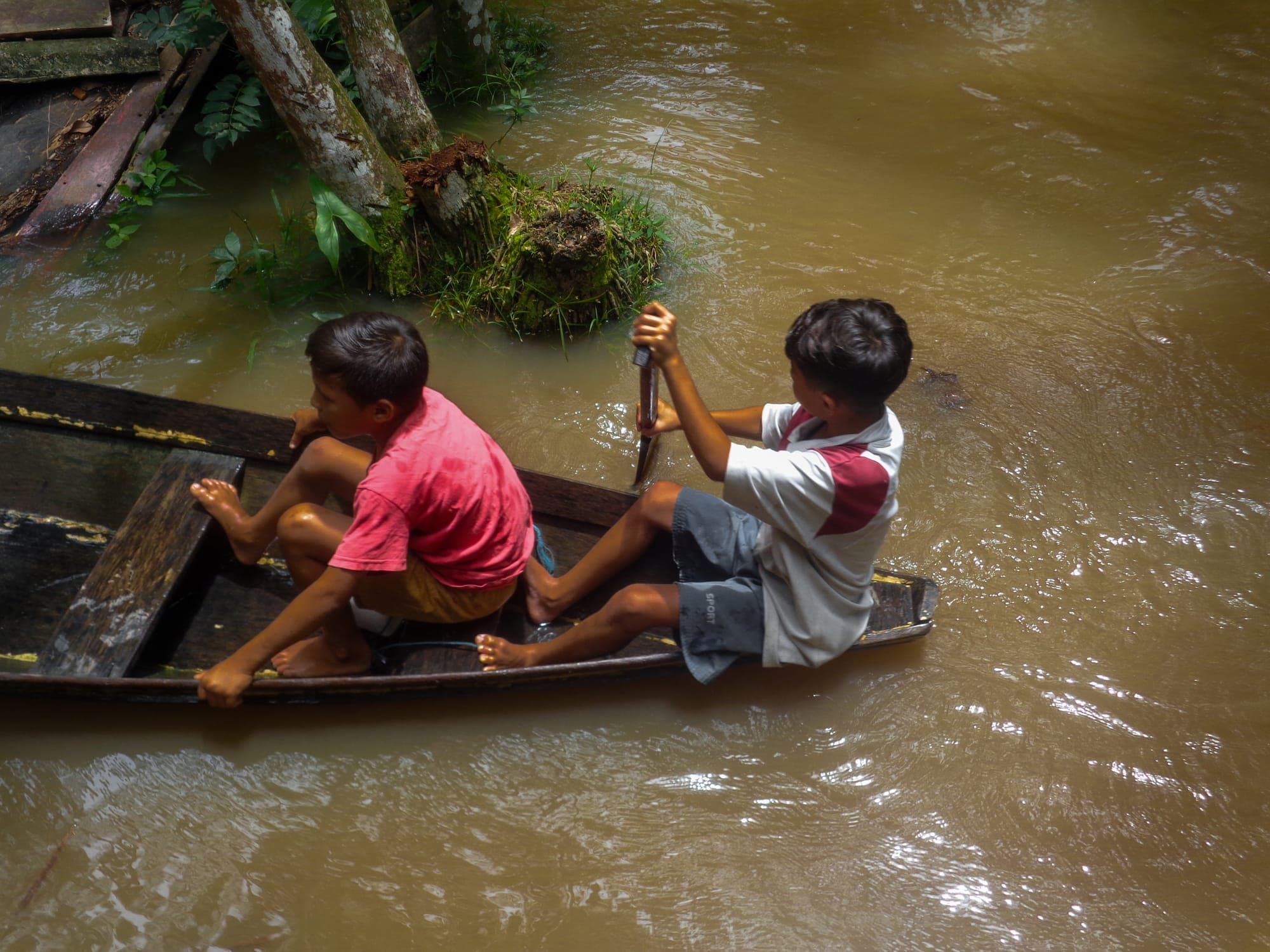Dois meninos remam uma canoa