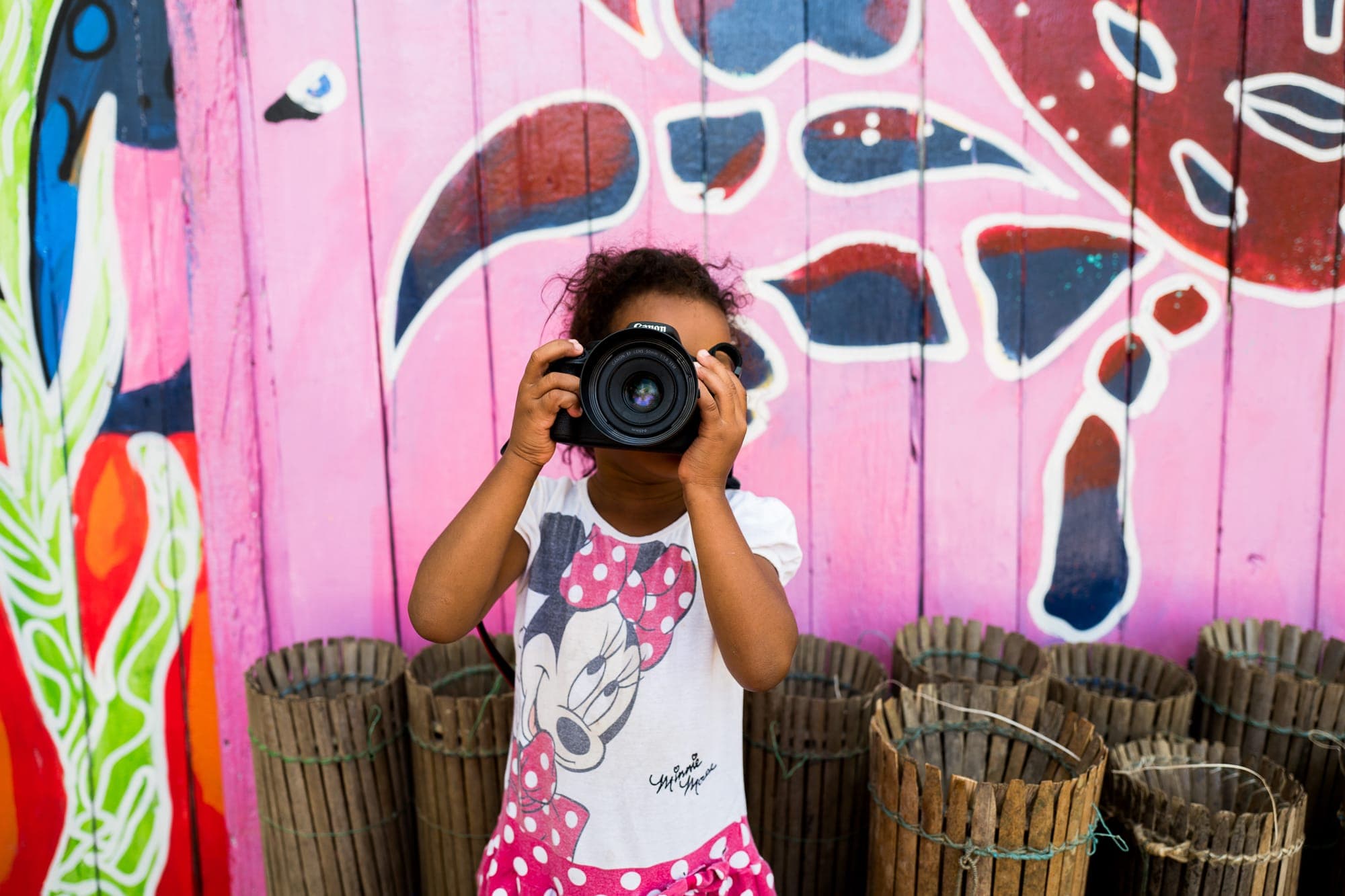 Menina fotografa diante de uma parede cor-de-rosa pintada