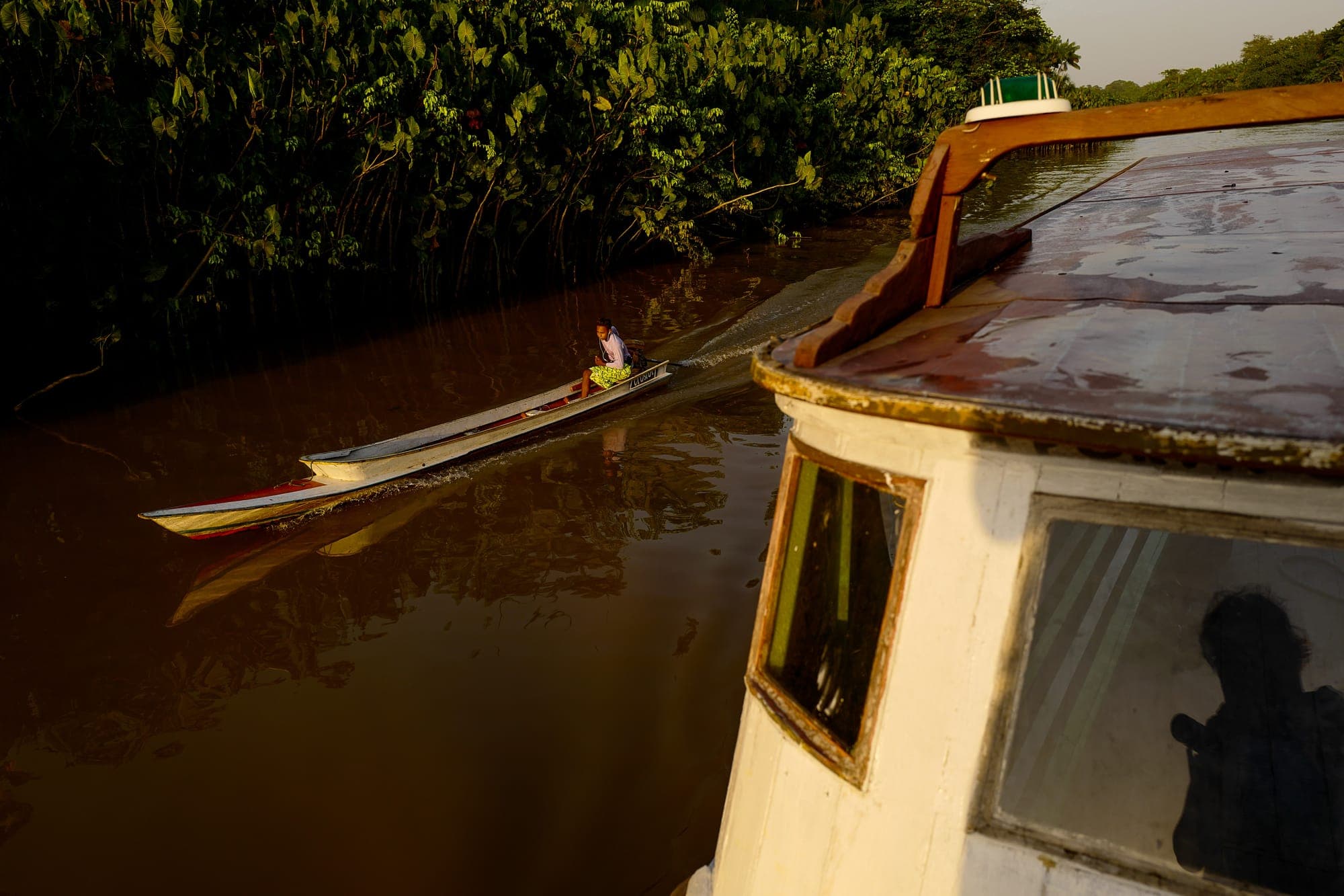 Canoa atravessa o rio ao lado de um barco maior