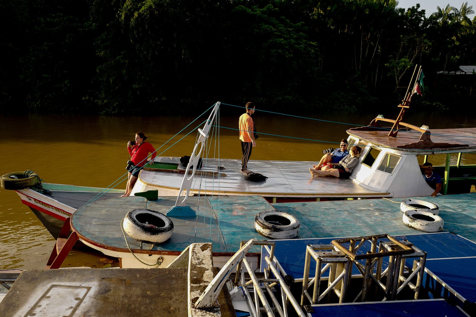 Barcos atracados em um trapiche, com moradores a bordo