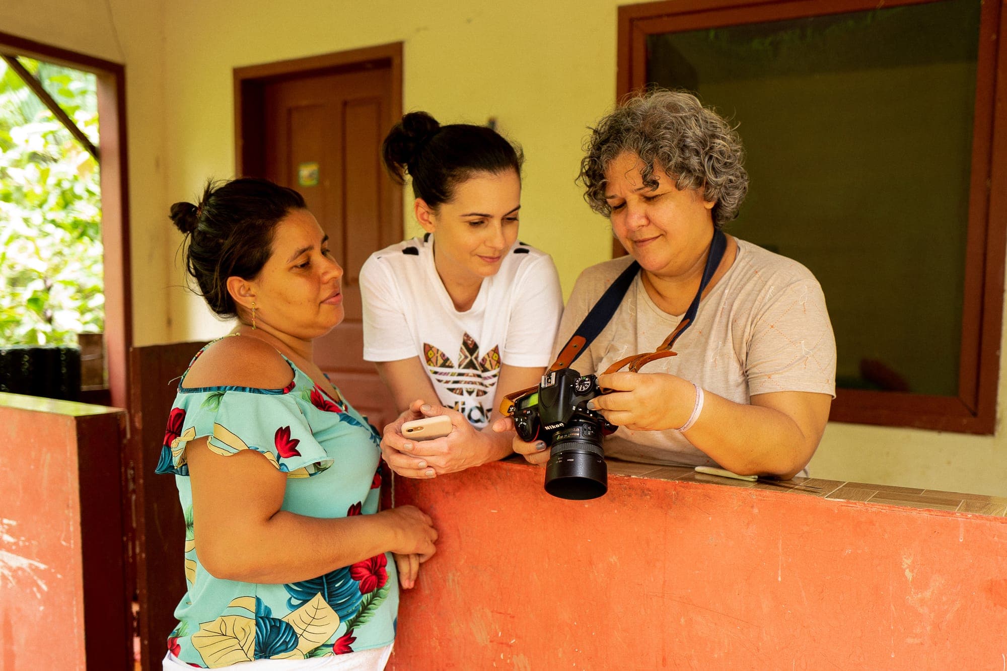 Participantes mostram fotos na câmera a uma moradora