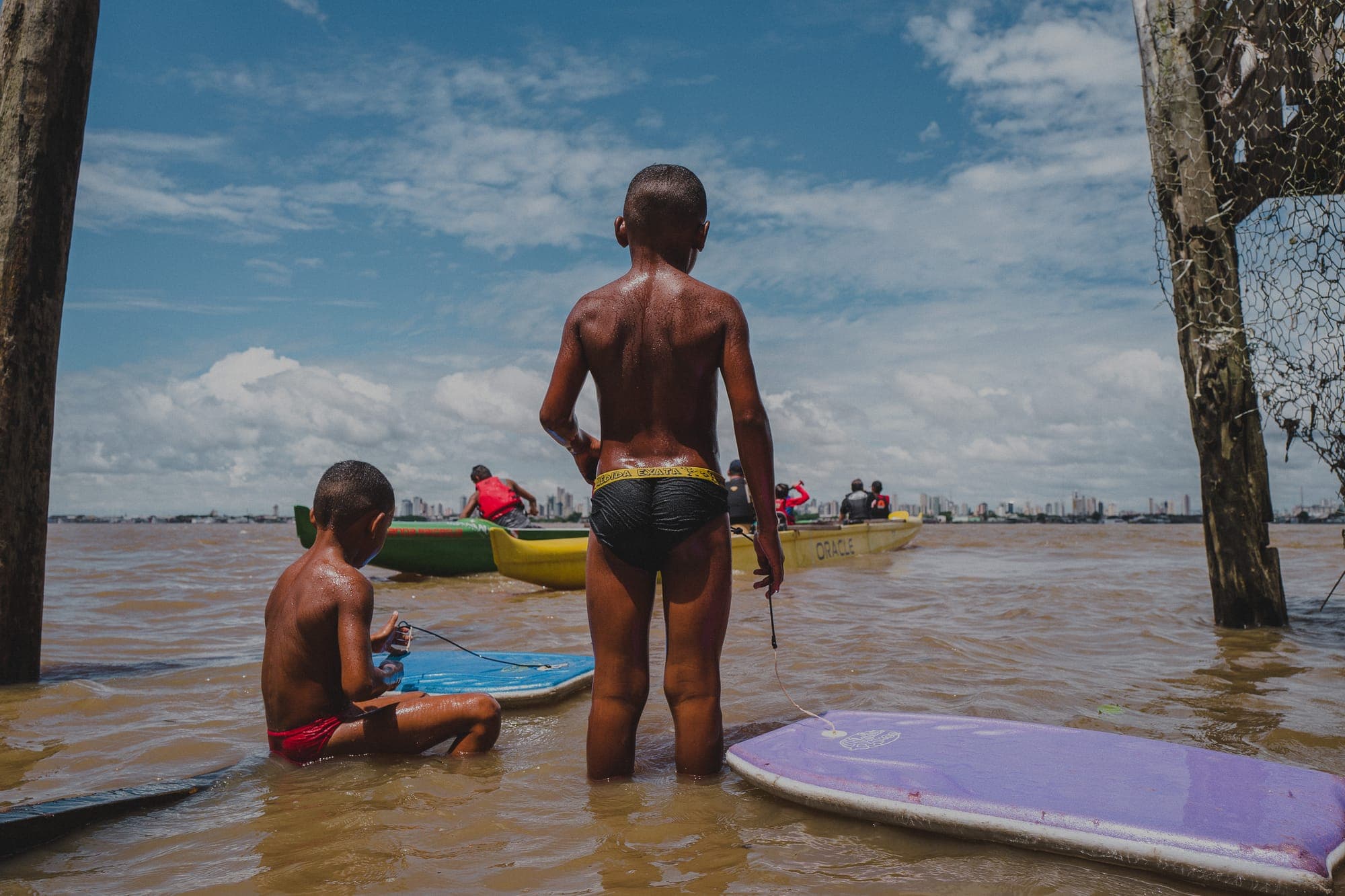 Crianças com pranchas na água rasa do rio