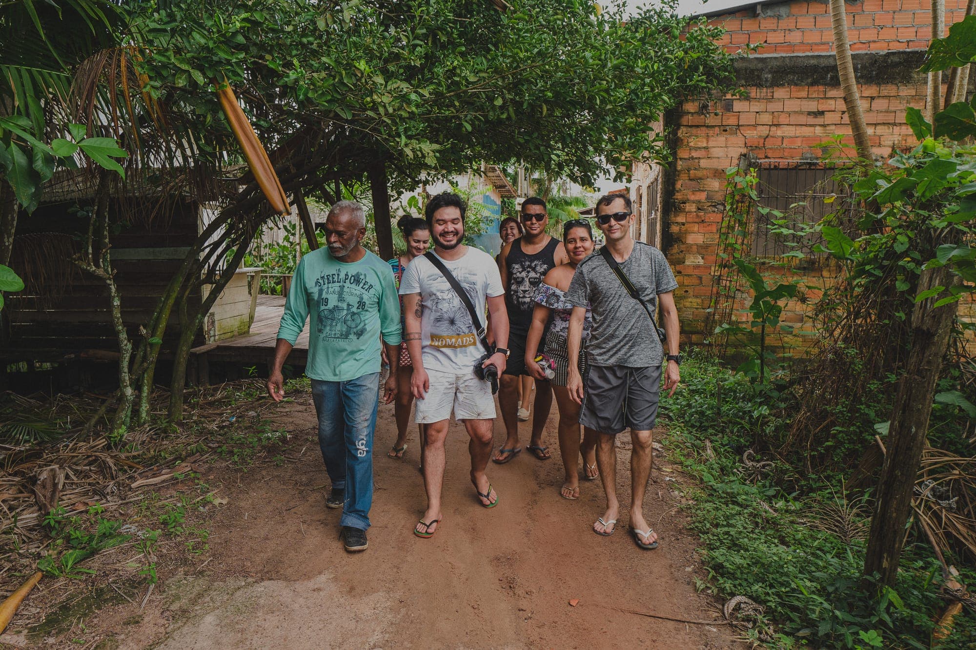 Grupo caminha por uma trilha de terra entre as casas