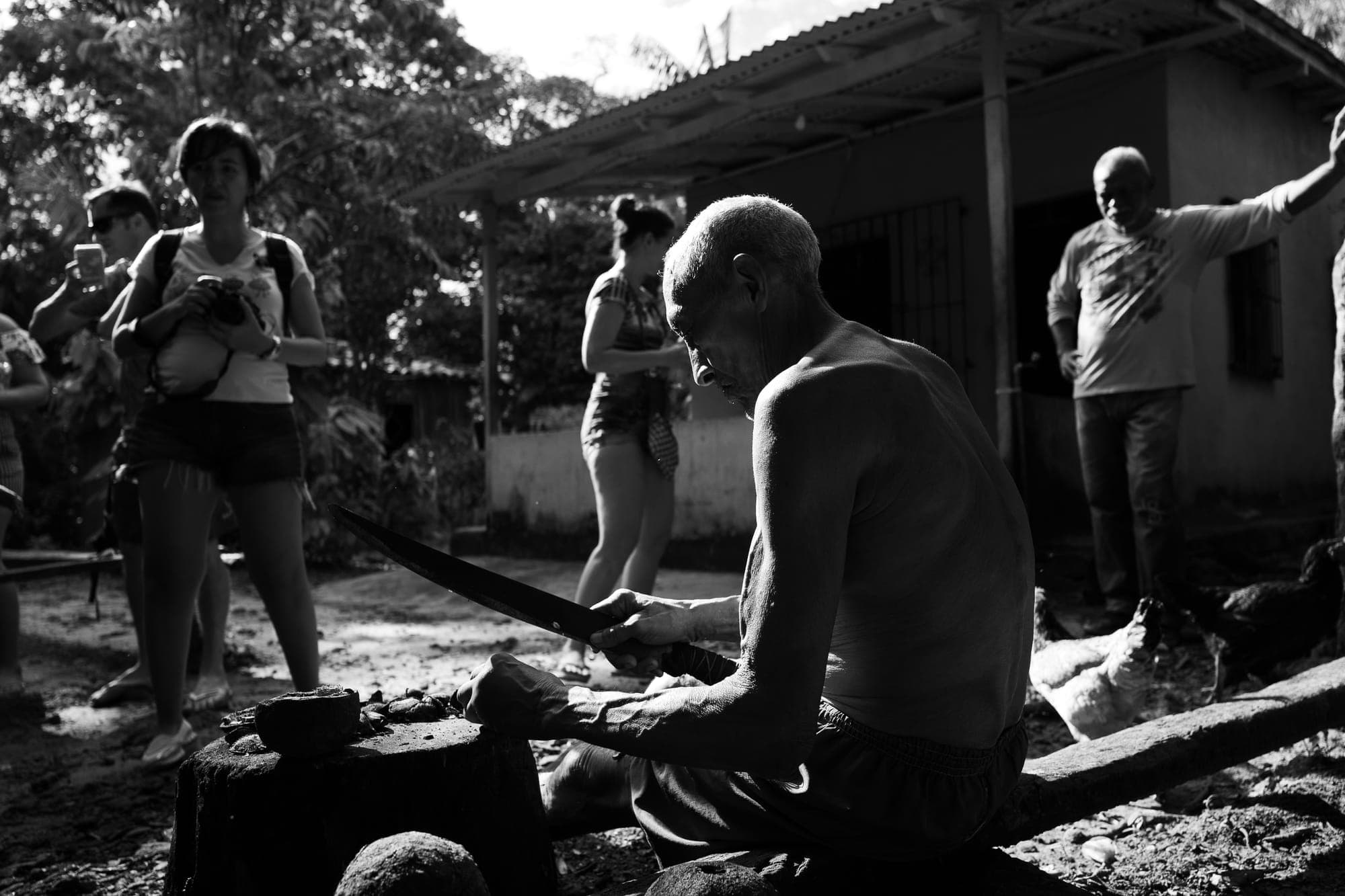 Participantes fotografam um morador trabalhando, em preto e branco